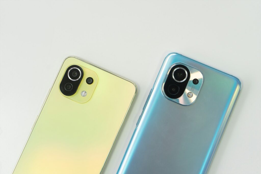 Dois celulares Xiaomi lado a lado, um verde e um azul, mostrando o conjunto de câmeras traseiras